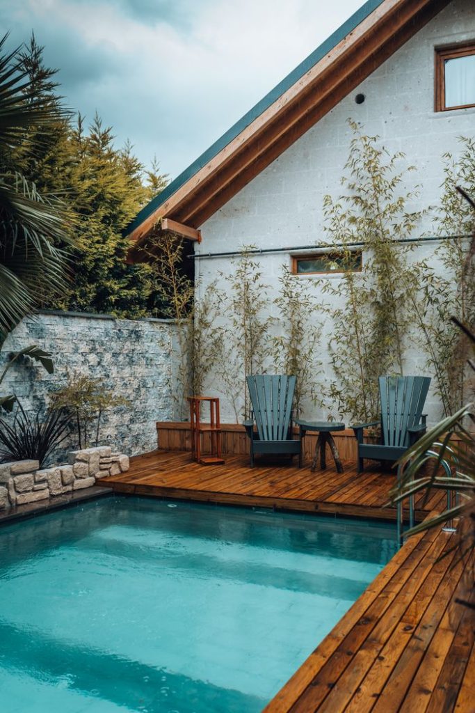 Cozy rustic setting with pool, chairs, and wooden deck. Ideal outdoor relaxation spot.