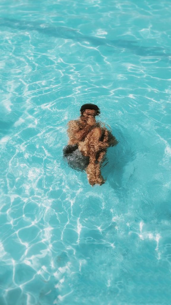 A man floats peacefully in a swimming pool, embracing the tranquil water on a sunny day.